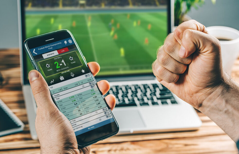 Man watching football play online broadcast on his laptop, cheering for his favourite team, making bets at bookmaker's website.